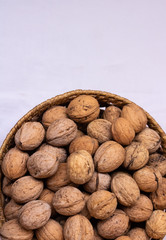 Walnut. Small wicker basket filled with walnuts on a white background