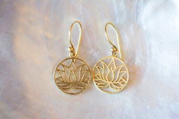 Brass earrings in lotus shape on shell background