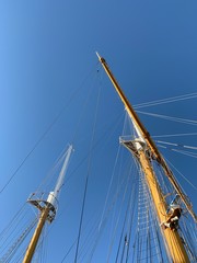 Wooden ship masts in the blue sky background