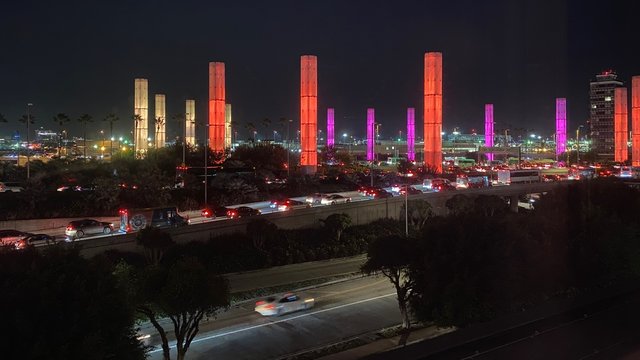LOS ANGELES, CA, JAN 2020: light columns glowing orange and pink at night, with traffic passing in foreground outside Los Angeles International Airport