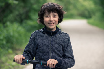 Obraz premium Portrait of a joyful boy with a scooter.