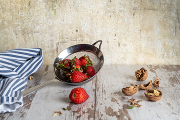 Strawberries and nuts in strainer with dishcloth