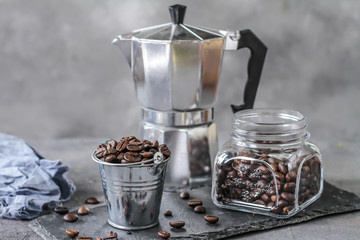 Photo of roasted coffee beans. Dark roasted. Spoon. Coffee pot. Glass cup. On rusty table. Gray background