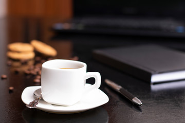 Fresh cup of cappuccino in a white cup of coffee, table with a pwn and a notebook