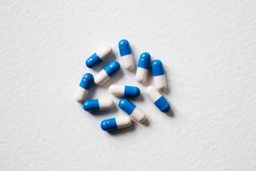Pile of blue-white capsules on white table. Course of treatment. Copy space. Flat lay, top view.