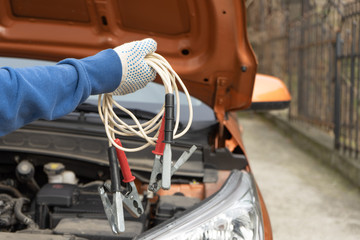 Fototapeta premium The jumper cable for car battery on the background of a vehicle with an open hood