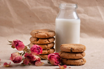 Homemade oatmeal cookies with nuts and chocolate and milk with flowers, still life
