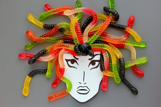Jelly worms or snakes candies lying like a woman's or a Gorgon's Medusa hair on a gray background. Creative concept of food, sweets.