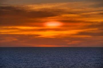 Naklejka na ściany i meble Timor Sea, Australai - December 1, 2009: Red sunset with brown cloudscape over dark blue sea. 