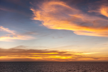 Fototapeta na wymiar Arafura Sea, Australai - December 2, 2009: Red sunset with brown to orange and yellow clouds in light to dark blue sky.
