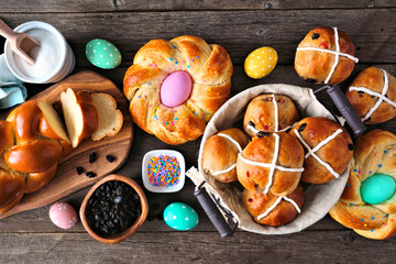 Easter table scene with a selection of fresh breads. Top view over a dark wood background. Spring holiday baking concept.