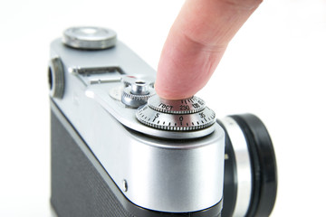 Old film retro camera. The fingers of a person push a button and trigger. Using the camera with hands, shooting close-up. Metallic black. White isolated background.