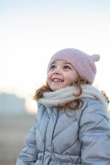 Adorable little girl smiles and looks at the sky.