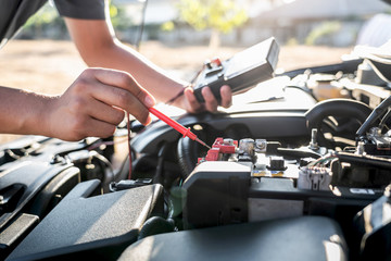 Mechanic repairman checking engine automotive in auto repair service and using digital multimeter testing battery to measure various values and analyze, Service and Maintenance car battery check