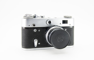 Old film retro camera with lens closed cap. Metallic black. White isolated background. Front side view