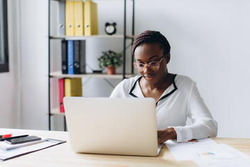 Pretty african american business woman working on laptop in office