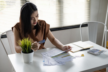 Young Asian woman is shocked stress and overthink by debt from many credit cards and bills.