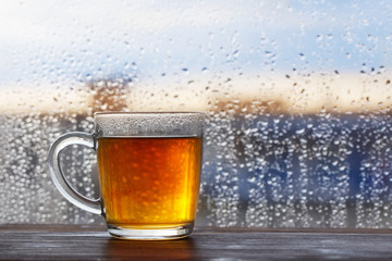 cup of tea on  background of  window with raindrops at sunset