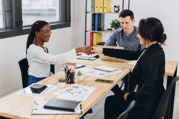 Young African beautiful woman having an interview or business meeting with employers in modern office interior