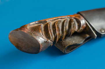 Old hunting knife in a scabbard on a blue background. Shooting from the side of the handle....