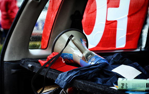 M&eacute;gaphone, casquette rouge et drapeaux syndicaux &agrave; l'arri&egrave;re d'un v&eacute;hicule lors d'une manifestation. Concept de lutte sociale, gr&egrave;ve et militantisme en France