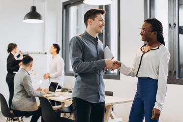 African businesswoman and Caucasian businessman have handshakes on the interracial team and modern office background
