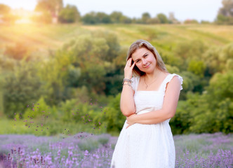 Fototapeta na wymiar woman in a white sundress walks in a lavender field and rests