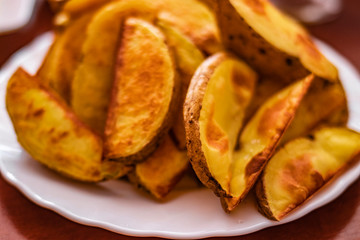 Close-Up Of Prepared Potatoes In white dish.Fried Potato Wedges on white dish a wood table.Directly Above Shot Of Fried Potatoes In Bowl.Fast food.Golden yummy Fried Potato Wedges,top view, lifestyle