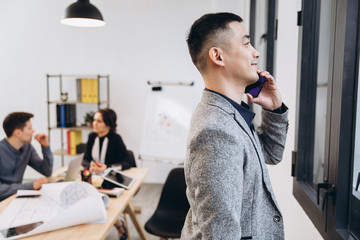 Asian business man talking on mobile phone in modern loft office