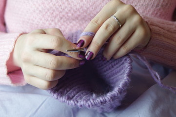 girl knitting scarf on spokes sitting on the sofa,
