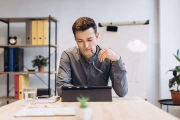 Young man sitting in office and working on desktop pc. Businessman looking at computer monitor while working in office.