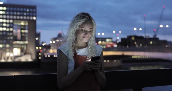 Pretty young woman typing message on smartphone, London, UK