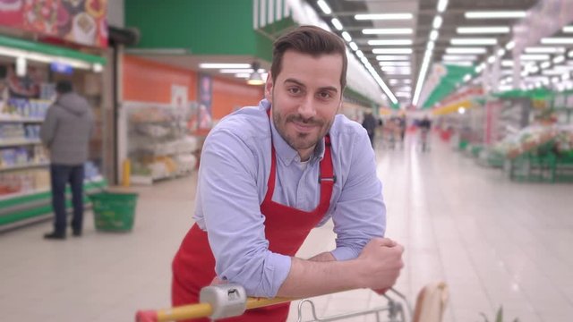 Portrait Of Happy Smiling Handsome Middle Aged Seller Man In Supermarket With Shopping Cart Positive Millennial Employee Looking At Camera, Smiling Face Satisfied With Good Job Successful People Story