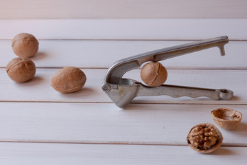 walnuts and nutcracker on a white wooden background