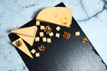 Pieces of cheese with walnuts on a dark background.