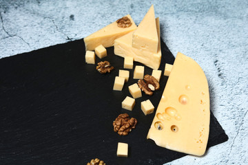 Pieces of cheese with walnuts on a dark background.