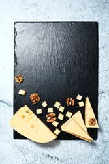 Pieces of cheese with walnuts on a dark background.