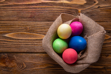 Easter composition. Colored eggs wrapped in burlap napkin on a wooden table.