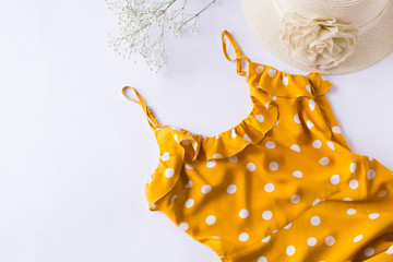 Yellow dress with white polka dot, hat and gypsophila on white background. Summer concept, fashion clothes. Flat lay, top view.