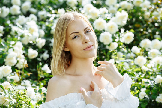 girl in a white dress in the garden with white roses