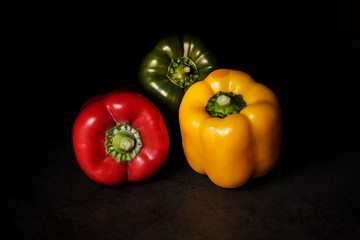 Front view of green, red and yellow peppers