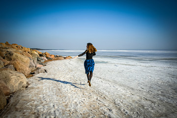 Girl runs on frozen water cover of Northern sea