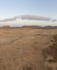 Vertical desert panorama with sand dunes, volcano mountains and the moon