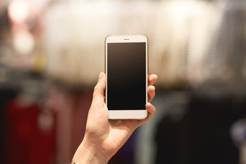 Faceless portrait of woman showing smart phone with blank screen in hand, copy space for advertisment or promotional text, young female holding mobile phone in one hand. Advertising concept.