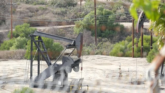 Industrial urban landscape. La Brea Inglewood in Los Angeles. Well pump jack operating behind the fence. Drilling rig extract crude oil. Oil mining machine with working piston. Oil and gas industry.