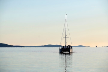 Silhouette of a sailing boat on calm see, in Split, Croatia.