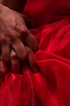 Hands of man and female pulling red sheets in ecstasy. Hands sign orgasm. Concept of passion, emotion and feeling.