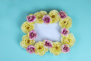 Envelope framed by yellow and pink flowers on tiffany blue  background.
