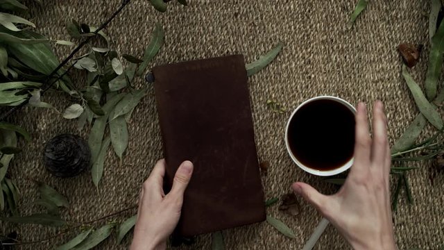 Flatlay with a wicker mat, dry plants, a notebook and a cup of coffee. Close-up of female hands writing in a notebook. Cup of coffee. Flatlay. Natural colors. Dry flowers. Eco-friendly aesthetics.