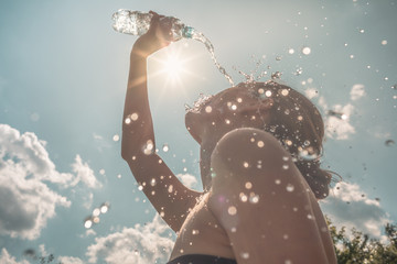 Young woman cooling off with water in the summer heat - Powered by Adobe